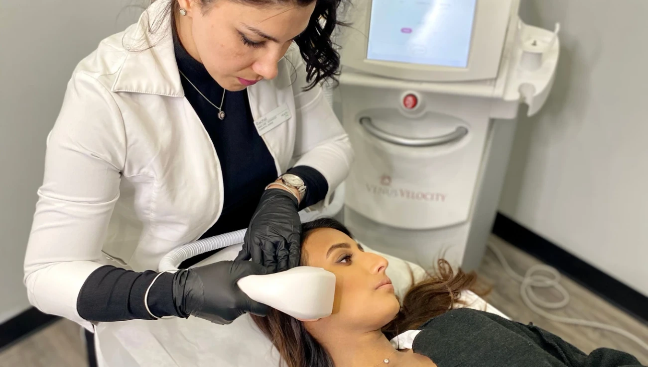 Aesthetician performing laser hair removal on a female patient