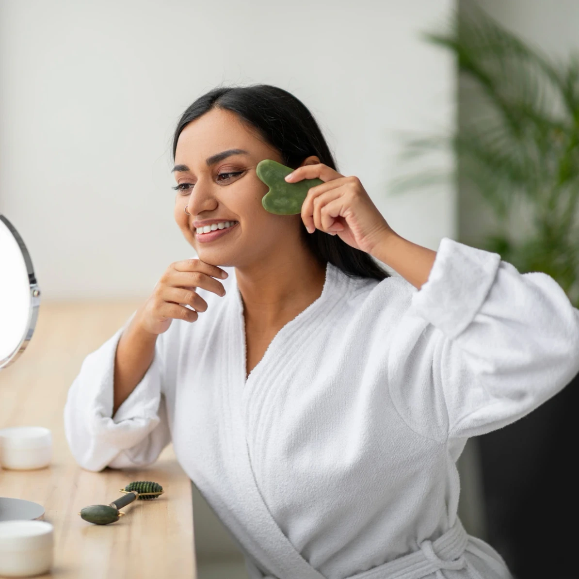 happy woman using a jade roller at home after skin treatment