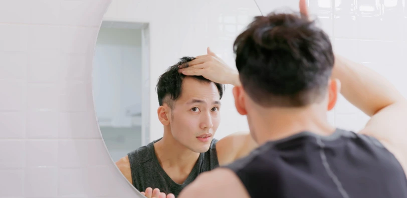 man+looking+in+mirror+assessing+hair+loss