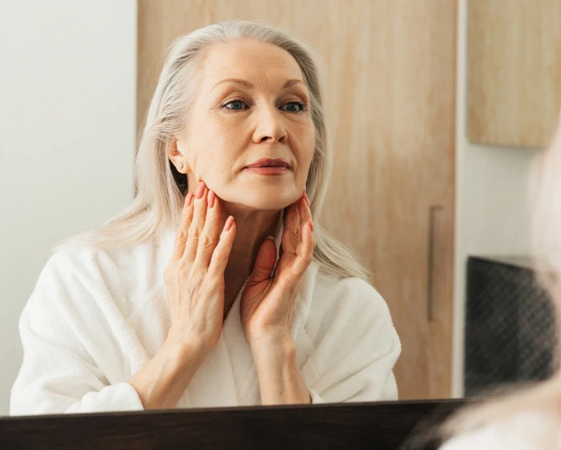 older woman looking at jaw in the mirror