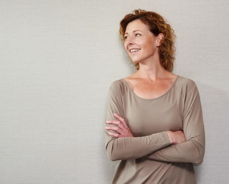 older woman smiling against a wall