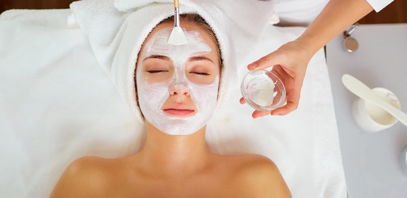 relaxed woman at skin clinic getting a face mask applied